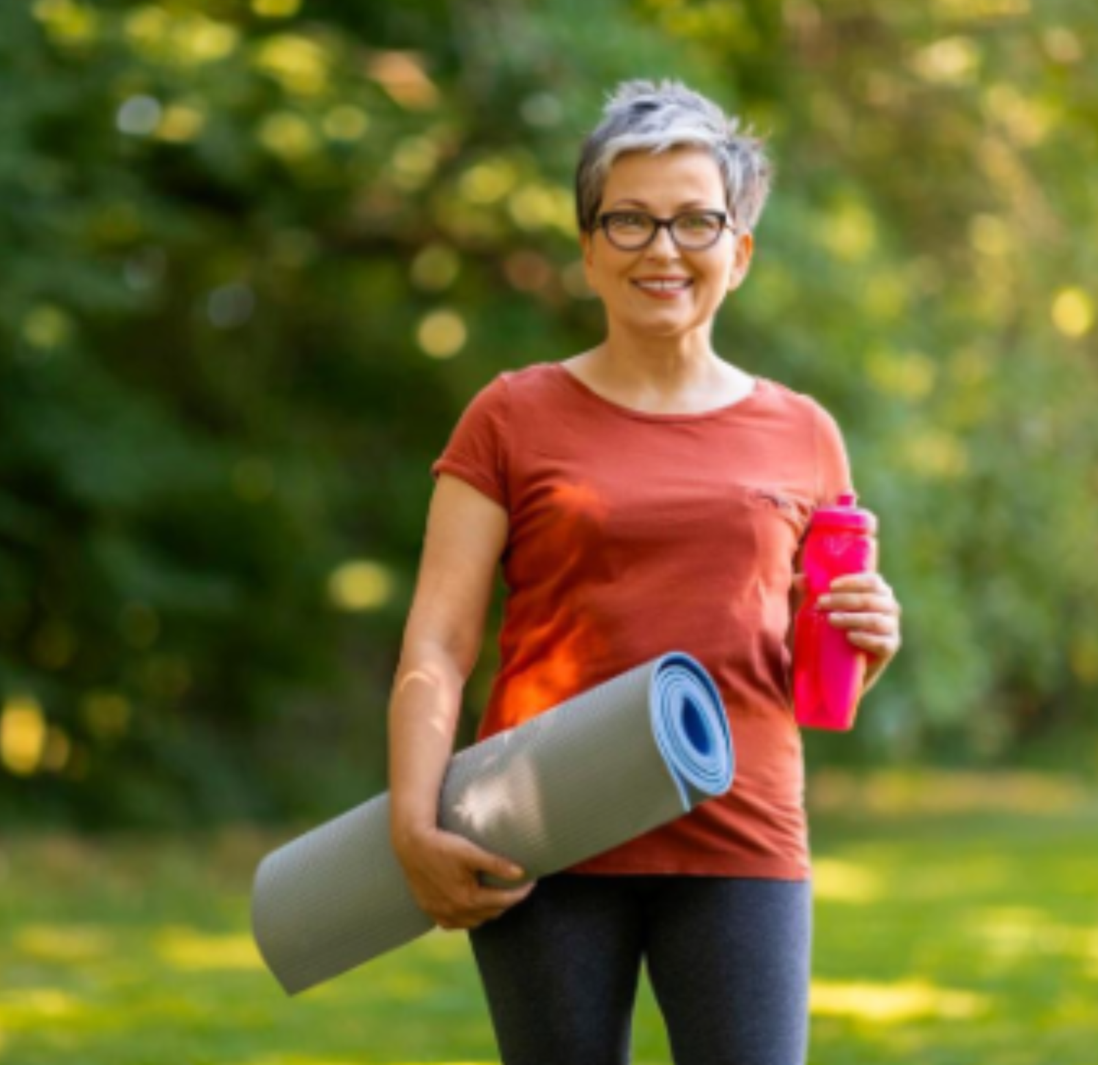 Active older woman outdoors carrying a yoga mat and water bottle